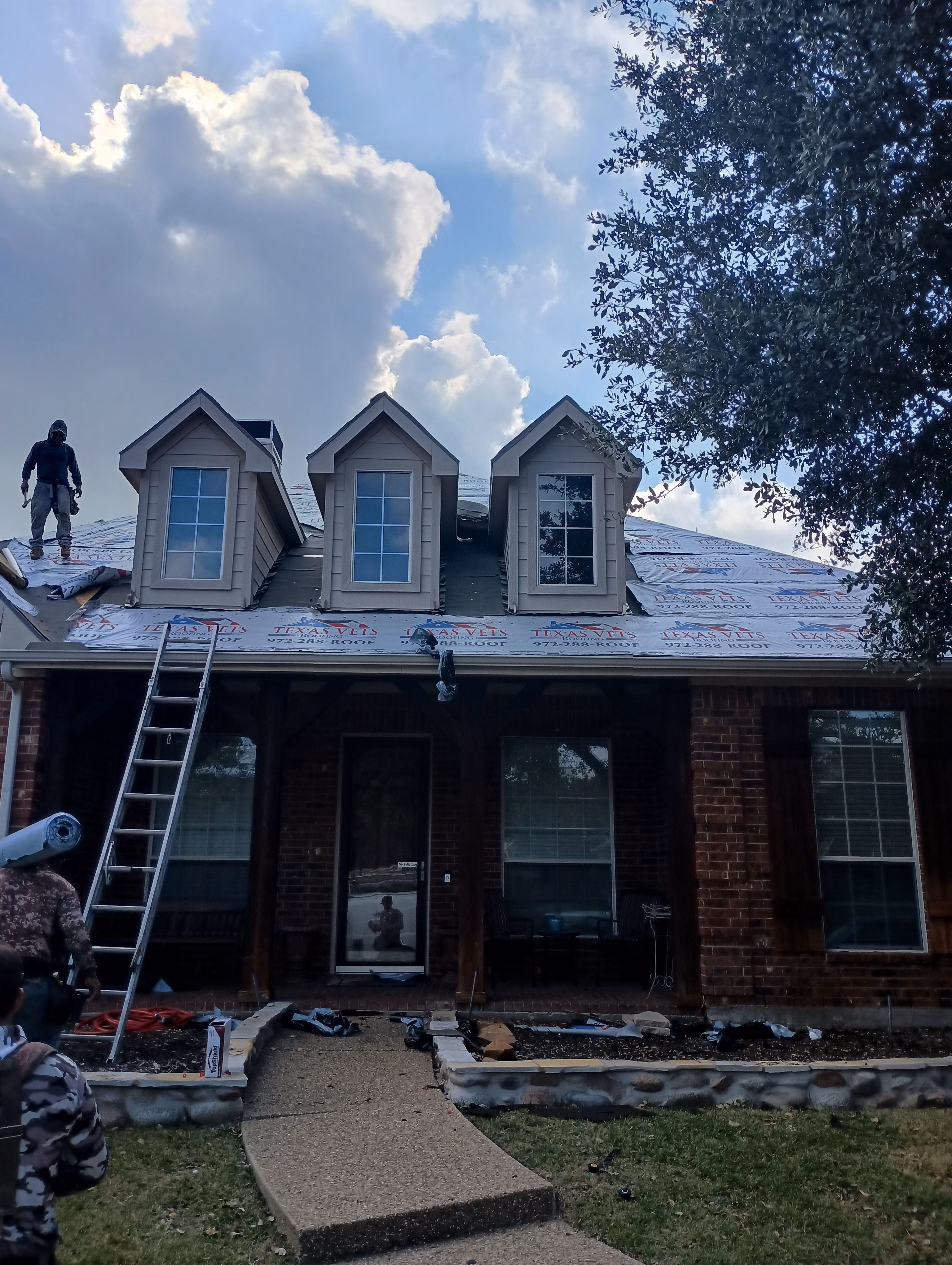 Texas Vets Roofing crew re-roofing a two-story brick DFW home with branded underlayment